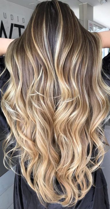 Long, wavy hair, balayage with a blend of light brown and blonde highlights.