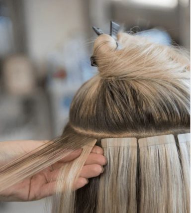A close-up of a person's hair being sectioned for extensions or styling.